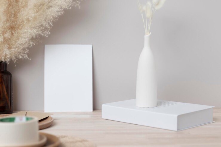 Blank paper card, greeting card mock up. decoration with dried Bunny Tail and pampas grass, Front view, Beautiful Bunny Tail grass in vase and white book on wood table and beige cement wall background