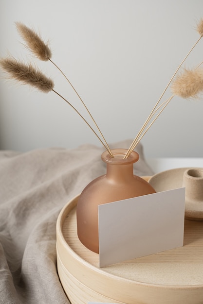 Blank paper card with bunny tail grass, wooden tray, neutral beige blanket