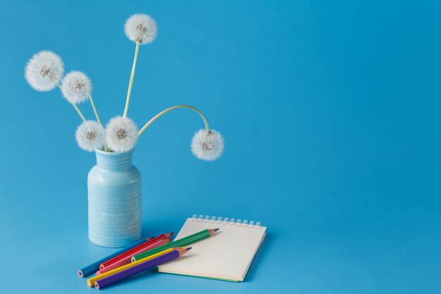 Blank paper and colorful pencils on blue table