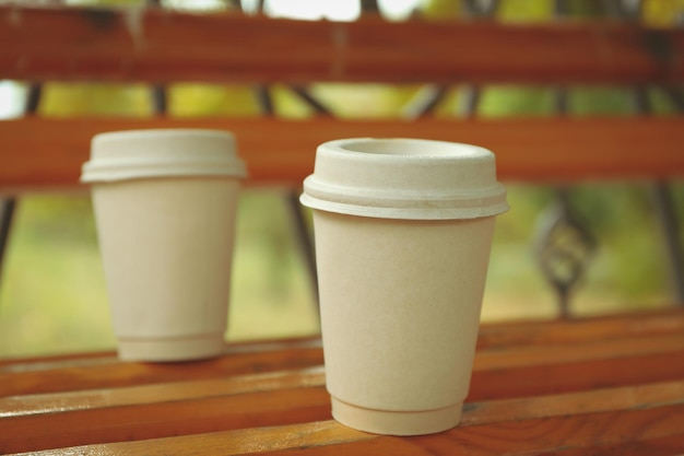 Blank paper cups on bench in park