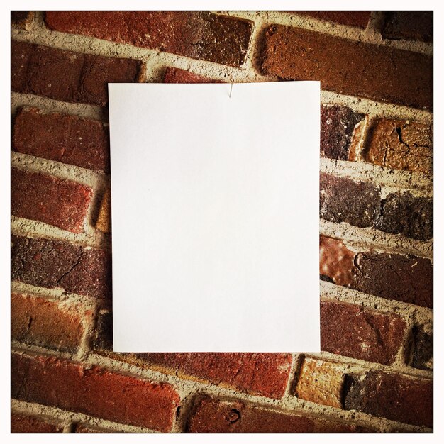 Photo blank paper hanging on brick wall