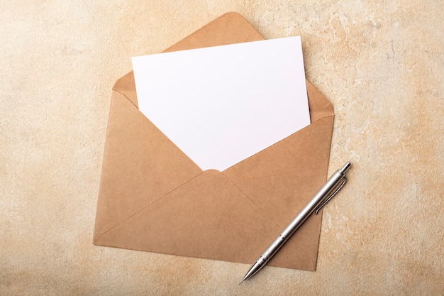 Чистый лист бумаги в конверте крафт на светлом фоне. Чистая открытка для ваших подписей. Вид сверху