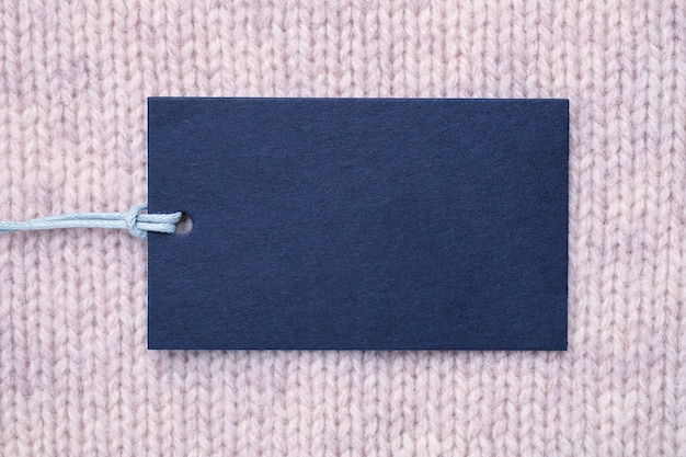 Blank paper label on knitted wool clothes background