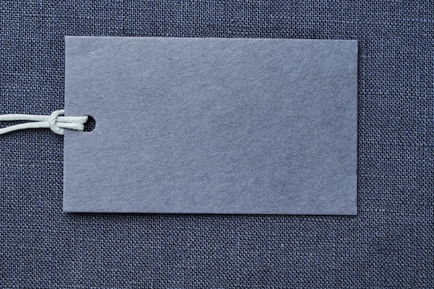 Blank paper label or price tag on blue linen clothes background