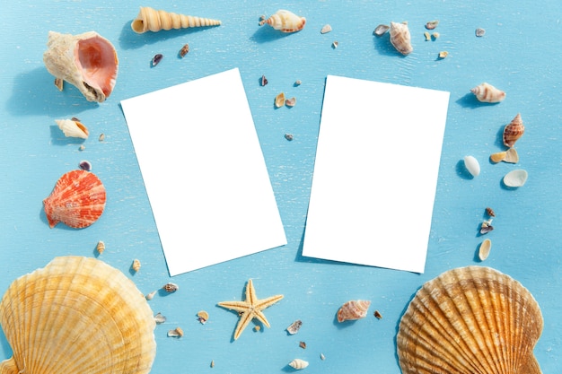 Blank paper photo frames with starfish, shells and items on wooden table.