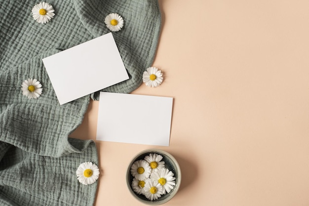 Blank paper sheet card with mockup copy space chamomile flower buds and aquamarine muslin cloth on neutral beige background Minimal aesthetic business brand template Flat lay top view