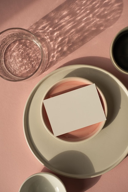 Scheda di foglio di carta bianca con spazio per la copia del mockup su sfondo rosa polveroso modello di marchio aziendale bohémien estetico piatti in ceramica e vetro con ombre scintillanti di luce solare