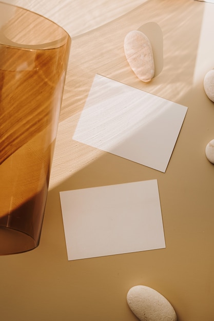 Blank paper sheet cards with tan glass vase with sunlight shadow on white