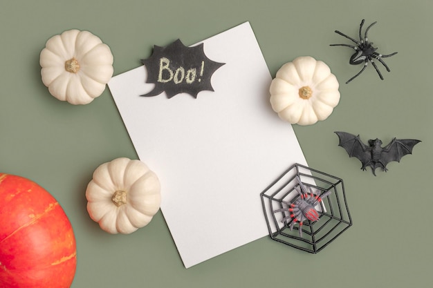 Blank paper sheet with Halloween decorations on pastel green background Greeting card invitation mockup Place for inscription Pumpkin Modern Minimal invite mock up template Flat lay top view