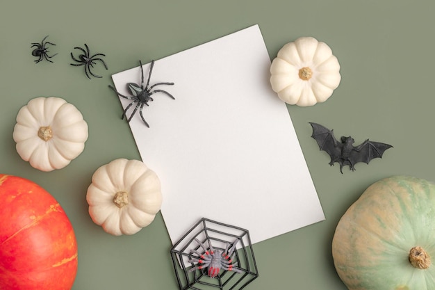 Photo blank paper sheet with halloween decorations on pastel green background greeting card invitation mockup place for inscription pumpkin modern minimal invite mock up template flat lay top view