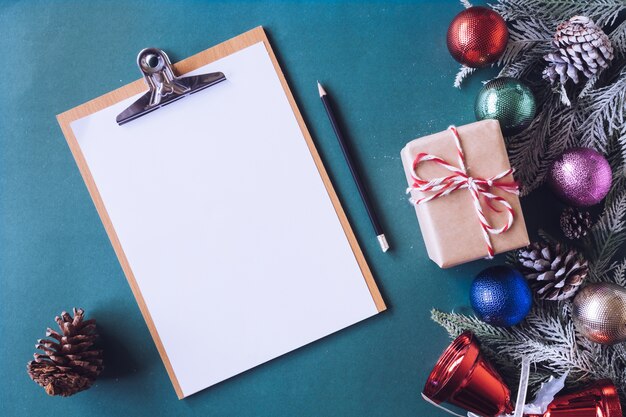 Blank paper with Christmas decoration on green background.