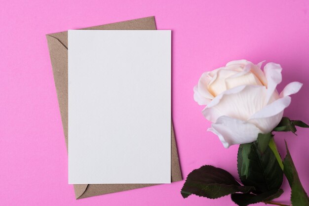 Foto carta bianca con fiori su uno sfondo rosa