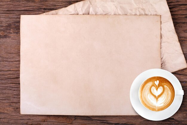 Carta bianca con la matita e una tazza di caffè su legno