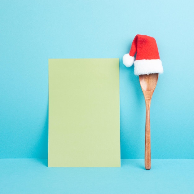 Blank paper with a wooden spoon and a red Santa Claus hat, christmas greeting card, copy space