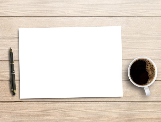 Blank paperpen and cup of coffee on brown wood table background