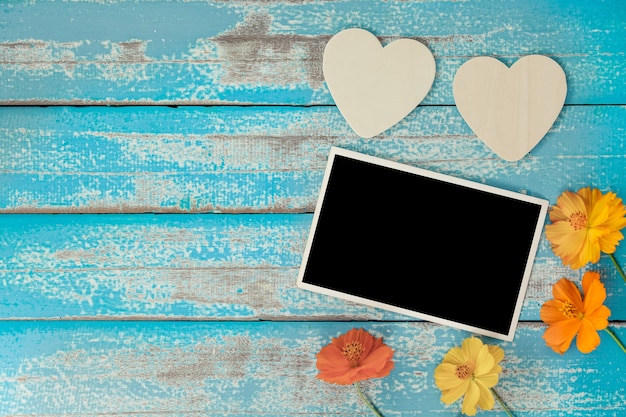 Blank photo frame album decorate with flower and heart shape on old blue wood background
