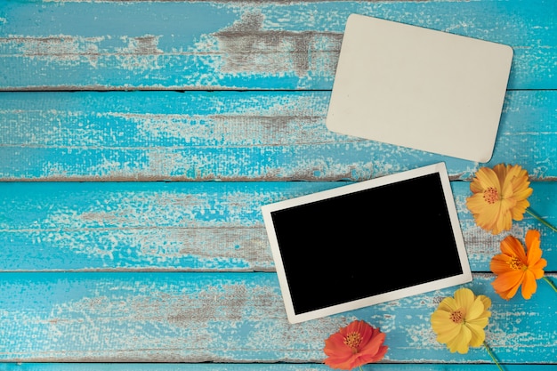 Blank photo frame album with flower on old blue wood background