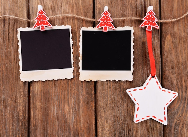 Blank photo frames and Christmas decor on rope on wooden background