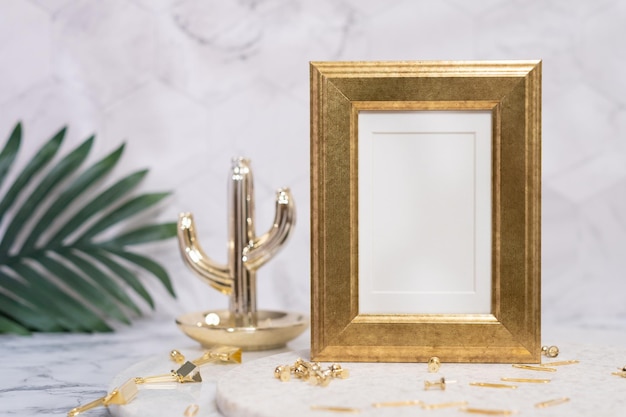 Blank picture frame on stone stand with gold stationery at whtie marble table background