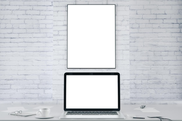 Blank picture frame on white brick wall and blank white laptop screen mock up