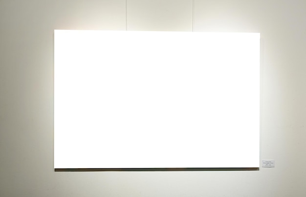 写真 灰色の壁の白い絵のフレームとギャラリーのモックアップの輝くランプ