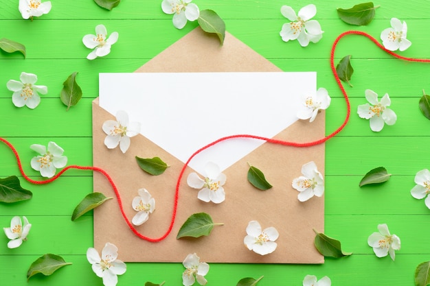 A blank piece of paper with an envelope on green wooden background