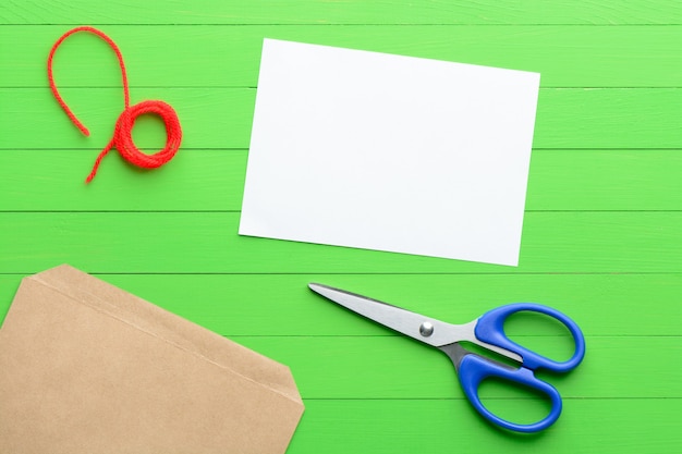 Foto un pezzo di carta bianco con una busta su fondo di legno verde