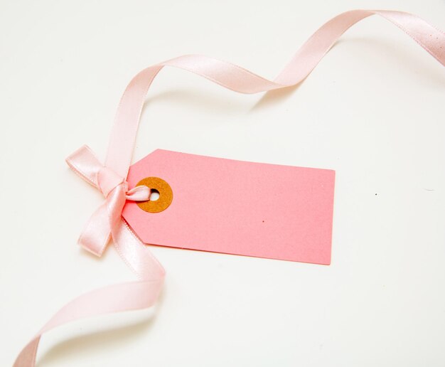 Blank pink price tag isolated on white background Pastel color empty gift card and curly ribbon bow