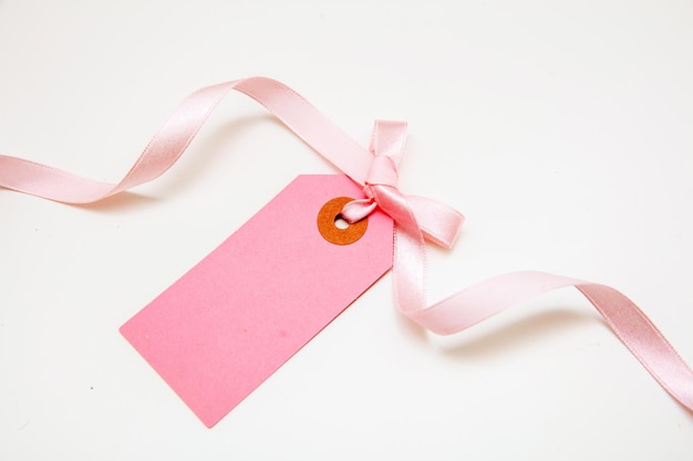 Blank pink price tag isolated on white background Pastel color empty gift card and curly ribbon bow