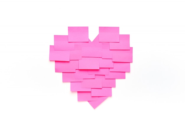 Пустые розовые наклейки на белой стене в форме сердца