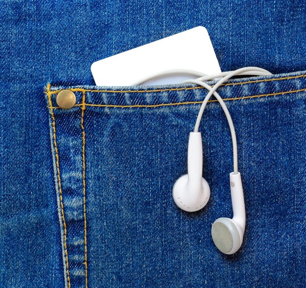 Blank plastic card and earphones hanging off a jeans pocket.