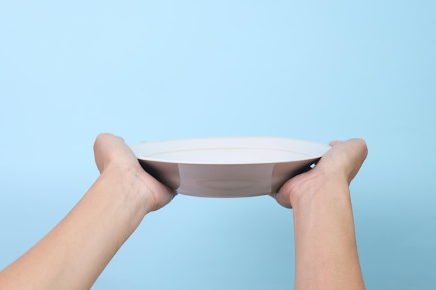 Photo blank plate in female hand isolated on blue background