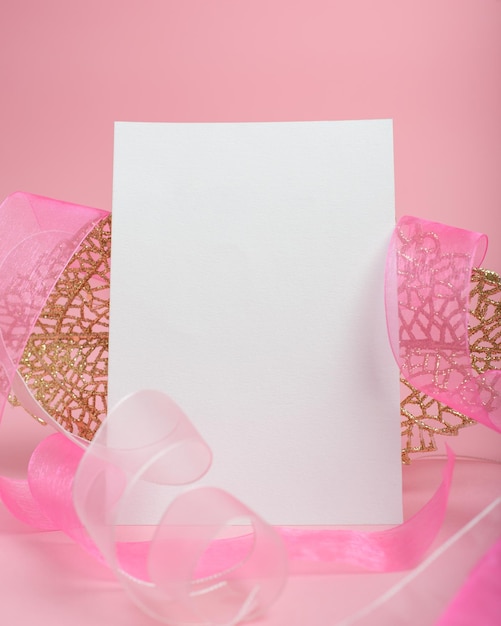 Blank postcard next to a pink ribbon on pink background Mockup