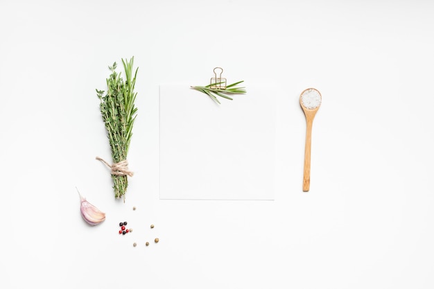 Blank recipe paper page with clip, greens herbs and spices