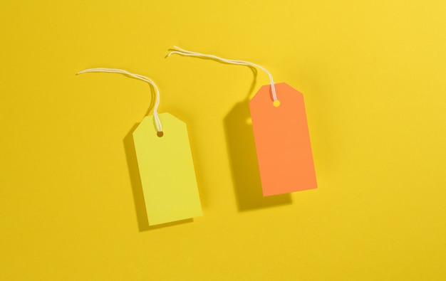사진 노란색 배경에 흰색 밧줄이 있는 빈 직사각형 용지 노란색 및 주황색 가격표, 위쪽 보기