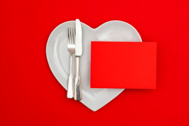 Blank red card on a heart shaped plate with knife and fork