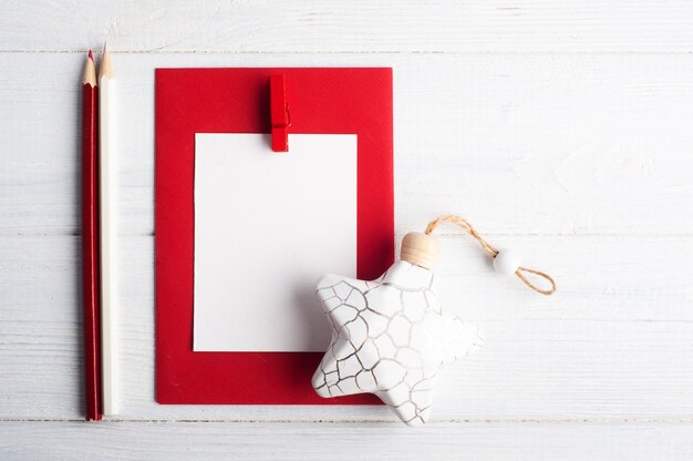 Blank red envelope, empty note and white Christmas toys on wooden rustic, flat lay