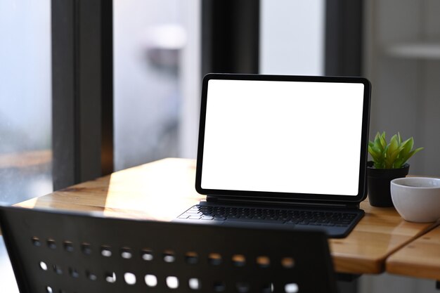 Blank screen digital tablet with wireless keyboard, coffee cup and plant