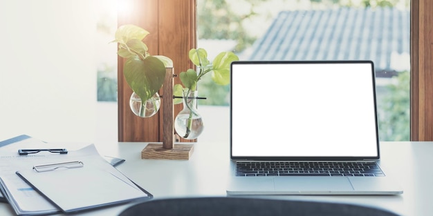 Blank screen Laptop computer and poster workspace background in modern office