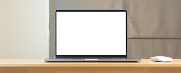 Blank screen laptop computer on wood table top in home office room