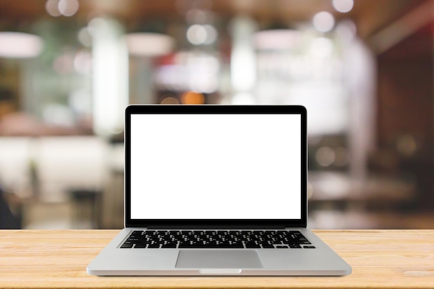 Blank screen laptop computer on wood table top with blur cafe restaurant background