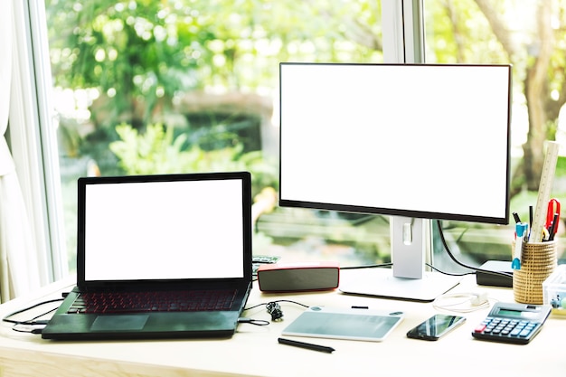 Photo blank screen of laptop and computer in workplace.