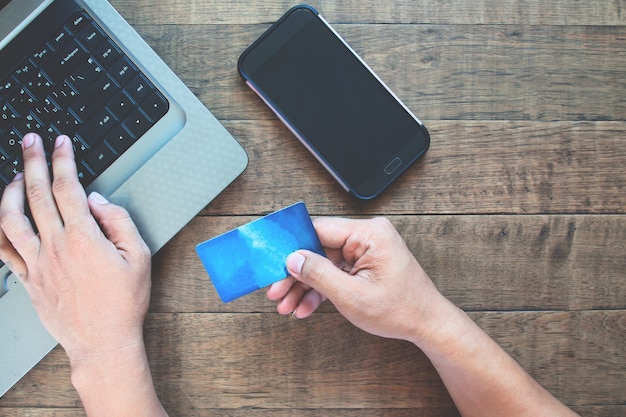 Blank screen smartphone for application mock up with man using credit card and laptop computer