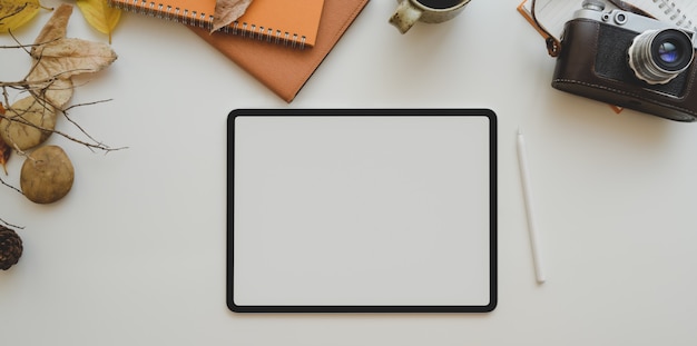 Пустой экран планшета и канцелярских принадлежностей на белом столе с копией пространства
