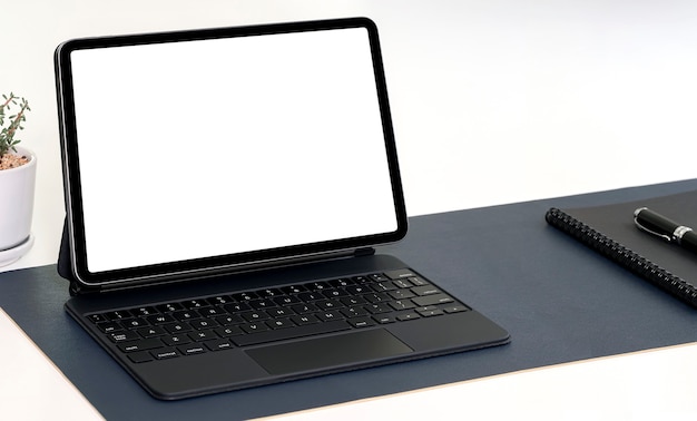 Blank screen tablet with keyboard on white table.