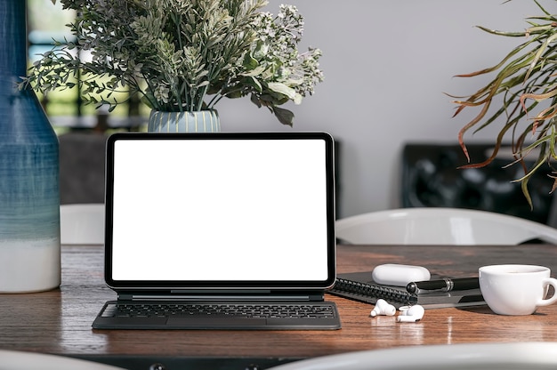 Blank screen tablet with keyboard on wooden table in cafe with sunlight in the morning.