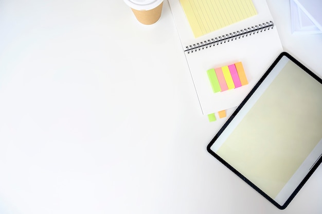 Blank screen tablet with supplies on white top table, copy space.