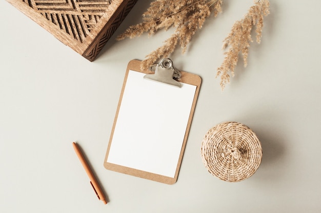 Blank sheet clipboard with empty copy space, pen, rattan casket on neutral