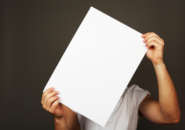 Blank sheet of paper in male hands on dark background