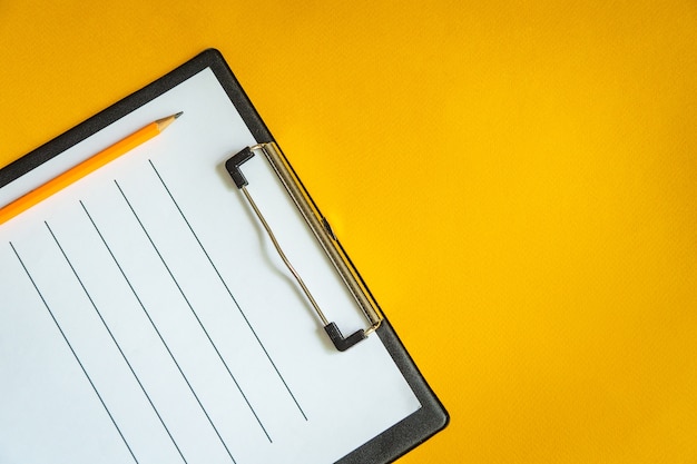 Blank sheet of paper and a pencil on yellow office Desk